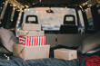 Many Christmas gifts in a van decorated with holiday festive lights.