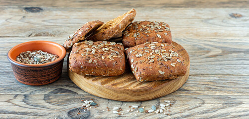 Wall Mural - Whole grain bread buns with seeds on a wooden background