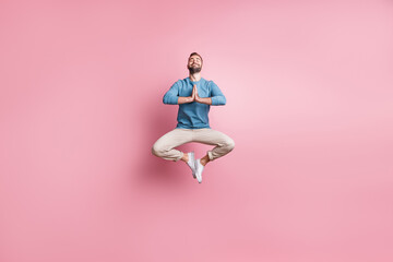 Wall Mural - Full length photo of sweet peaceful young guy wear blue pullover jumping enjoying yoga isolated pink color background