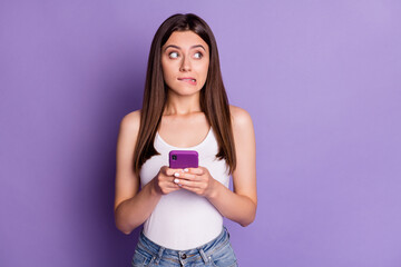 Wall Mural - photo of charming woman look empty space uncertain write comment use phone isolated on violet color 