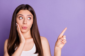 Wall Mural - photo portrait of funny pouting girl pointing finger at blank space isolated on vivid violet colored