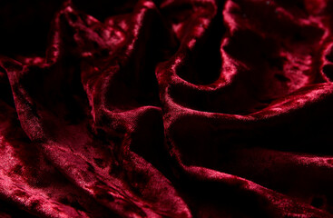 Red velvet material background. Beautiful swirl fabric texture