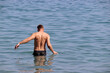 Man going to swim in a sea, back view. Beach vacation and water leisure