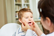 Ärztin untersucht Hals und Zunge bei Kind