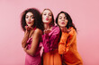 © Look! - Group of women sending air kisses on pink background. Half length portrait of three girls of mixed race.