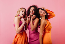 Group Of International Friends Posing In Studio. Infoor Photo Of Three Women In Bright Dresses.