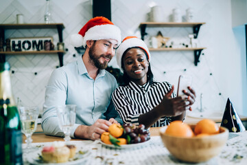 Wall Mural - Smiling multiethnic adult couple taking selfie at New year party