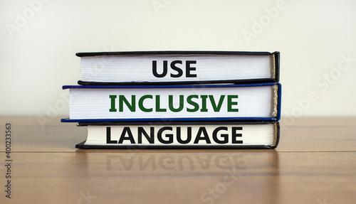 Use inclusive language symbol. Books with words 'Use inclusive language' on beautiful wooden table, white background. Business and use inclusive language concept. Copy space.