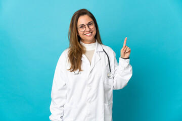 Middle age Brazilian doctor woman isolated on blue background showing and lifting a finger in sign of the best