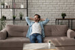 © fizkes - Lazy morning. Successful millennial man relaxing on comfy sofa at home after finishing work looking aside with glad smile. Calm young guy taking pleasure in awaited weekend enjoying peaceful dreams
