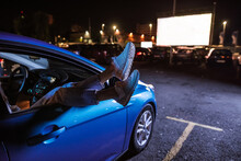 Close Up Of Woman S Legs Dangling Out A Car Window Parked In Front Of A Big White Screen At Drive In Cinema