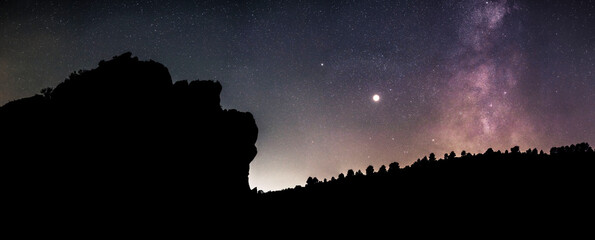 Wall Mural - An ancient look at the universe. The silhouette of a face sculpted in the mountain, the planet Jupiter and the milky way. A face is the starry night watch the milky way and the stars. Night panoramic.