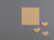 Hearts And Writing Sheet.
Three Yellow Hearts And A Sheet For Writing On The Right On A Dark Gray Background With A Place For Text, Top View, Close-up.