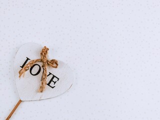 Wall Mural - Wooden heart.

Wooden heart with the inscription love and a jute rope on the left on an abstract background with a place for text on the right, top view close-up.