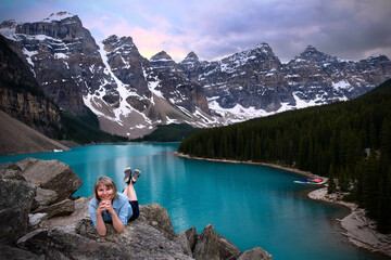 Wall Mural - Woman tourist relaxing on cliff above Moraine lake in Canadian Rockies. Banff National Park. Alberta. Canada 