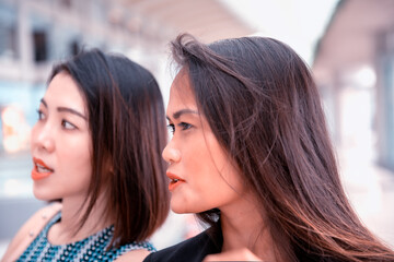 Two beautiful young asian friends in a mall shopping center standing and talking