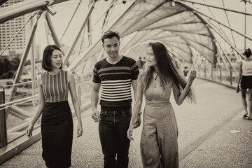 Sticker - Three happy young asian friends outdoor standing and walking along city bridge