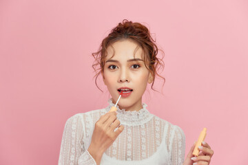 Wall Mural - Woman with lip gloss. Photo of woman with perfect makeup on pinkbackground. Beauty concept