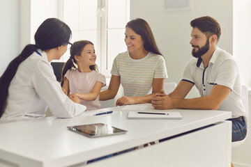 Wall Mural - Happy family with daughter sitting during woman doctor visit in medical clinic