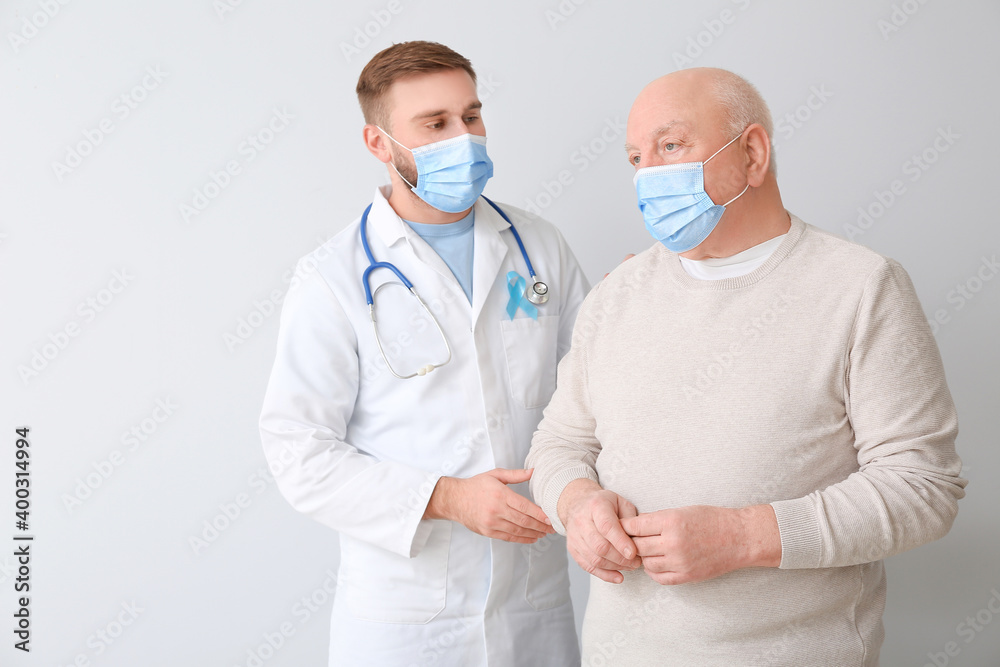 Doctor and senior man on light background. Prostate cancer awareness concept