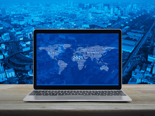 Start up 2021 business icon with global words world map with modern laptop computer on wooden table over city tower, street, expressway and skyscraper, Happy new year 2021 global business start up con