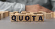 The word QUOTA made from wooden cubes. Shallow depth of field on the cubes