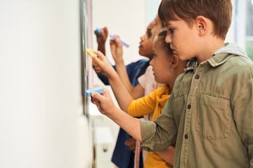 Little first graders writing text on blackboard at the school