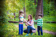 © pahis - Young woman mother applying insect repellent to her two son before forest hike beautiful summer day or evening. Protecting children from biting insects at summer. Active leisure with kids