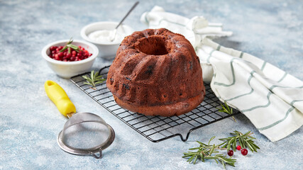 Poster - Chocolate bundt cake on a metal wire rack, powdered sugar and cranberries in bowls