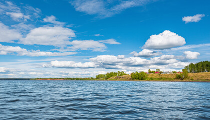 Wall Mural - panorama of a calm lake, the kama river, blue sky with clouds reflected in the water. a village on t