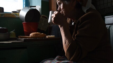 Wall Mural - Unhappy wrinkled woman looking in window and drinking from cup in loneliness