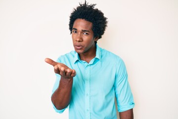 Poster - Handsome african american man with afro hair wearing casual clothes looking at the camera blowing a kiss with hand on air being lovely and sexy. love expression.