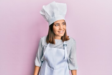 Sticker - Young beautiful woman wearing professional cook uniform and hat looking away to side with smile on face, natural expression. laughing confident.