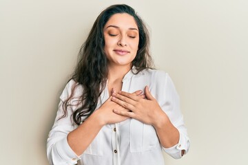 Beautiful middle eastern woman wearing casual clothes smiling with hands on chest with closed eyes and grateful gesture on face. health concept.