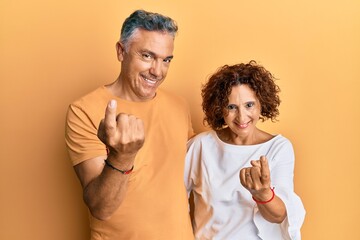 Wall Mural - Beautiful middle age couple together wearing casual clothes beckoning come here gesture with hand inviting welcoming happy and smiling