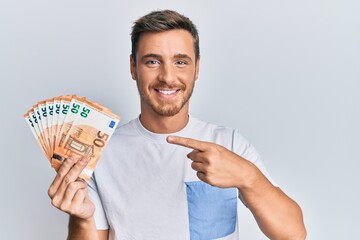 Poster - Handsome caucasian man holding 50 euro banknotes smiling happy pointing with hand and finger