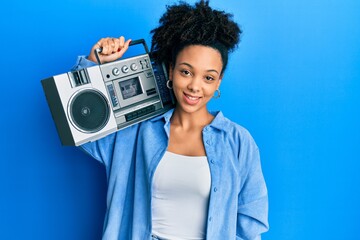 Poster - Young african american girl holding boombox, listening to music looking positive and happy standing and smiling with a confident smile showing teeth