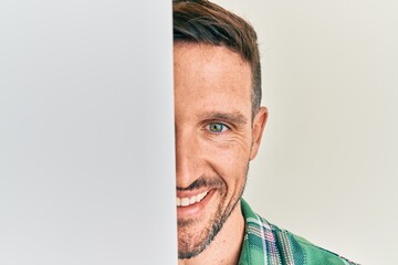 Sticker - Handsome man with beard holding blank empty banner covering half face smiling with a happy and cool smile on face. showing teeth.