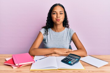 Canvas Print - Young african american girl accountant working at the office puffing cheeks with funny face. mouth inflated with air, crazy expression.