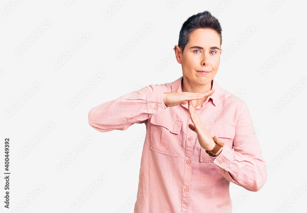 Young woman with short hair wearing casual clothes doing time out gesture with hands, frustrated and serious face