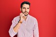 © Krakenimages.com - Young hispanic man wearing business shirt serious face thinking about question with hand on chin, thoughtful about confusing idea