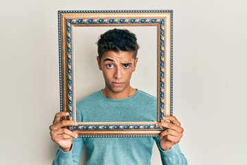 Sticker - Young handsome african american man holding blank empty banner skeptic and nervous, frowning upset because of problem. negative person.