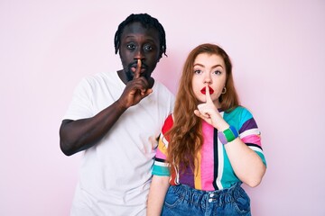 Wall Mural - Interracial couple wearing casual clothes asking to be quiet with finger on lips. silence and secret concept.