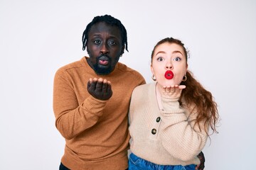 Poster - Interracial couple wearing casual clothes looking at the camera blowing a kiss with hand on air being lovely and sexy. love expression.