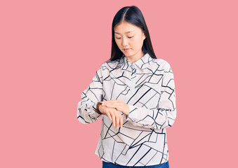 Poster - Young beautiful chinese woman wearing casual shirt checking the time on wrist watch, relaxed and confident