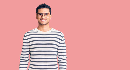 Wall Mural - Hispanic handsome young man wearing casual clothes and glasses with a happy and cool smile on face. lucky person.