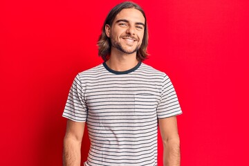 Young handsome man wearing casual clothes looking positive and happy standing and smiling with a confident smile showing teeth