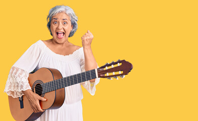 Poster - Senior woman with gray hair playing classical guitar screaming proud, celebrating victory and success very excited with raised arms