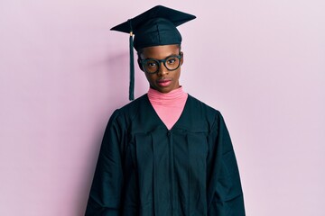 Canvas Print - Young african american girl wearing graduation cap and ceremony robe relaxed with serious expression on face. simple and natural looking at the camera.