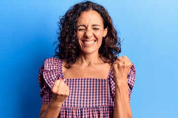 Wall Mural - Middle age beautiful woman wearing casual t shirt celebrating surprised and amazed for success with arms raised and eyes closed